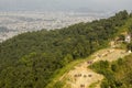 A people walk along the path to the top of the mountain with a green forest on the background of the city in the valley below the Royalty Free Stock Photo