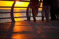 People walk along the promenade in the yellow and orange rays of the sun at sunset. Royalty Free Stock Photo