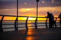 People walk along the promenade in the yellow and orange rays of the sun at sunset. Royalty Free Stock Photo