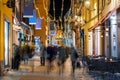 People walk along a street illuminated by Christmas lights.