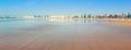 People walk along wide empty coastline of beautiful Essaouira Beach