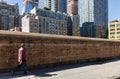 People walk along a yellow brick fence in NYC