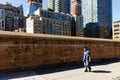 People walk along a yellow brick fence in NYC