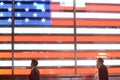 People walk by American Flag light Time Square