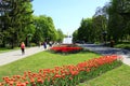 People walk in the park with flower beds and fountains