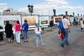 People walk on Patriarshy bridge in Moscow and watch photographs