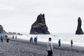 People walk on Reynisfjara black sand lava beach