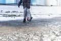 People walk on a slippery road made of melted ice. View of the legs of a man walking on an icy pavement. Winter road in the city. Royalty Free Stock Photo