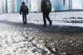 People walk on a slippery road made of melted ice. View of the legs of a man walking on an icy pavement. Winter road in the city. Royalty Free Stock Photo