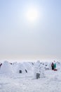 People walk on snow-covered lake among the igloos built for the contest, the traditional shelter of the northern peoples from