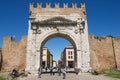 People walk under Augustus Arch - the ancient romanesque gate and the historical landmark of Rimini, Italy.