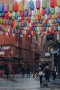 People walk under rainbow coloured lanterns on a street in Chinatown, London, UK