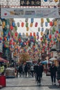 People walk under rainbow coloured lanterns on a street in Chinatown, London, UK