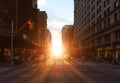 People walking across the busy intersection with sunset light shining in the background on 23rd Street in New York City