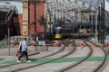 People walking across a crossing point on the tracks with yellow electric tram in the background at entrance to station Royalty Free Stock Photo