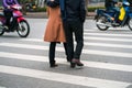 People walking across a street while motorbikes keep running on street in Hanoi, Vietnam. Closeup