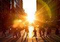 People walking across the street in New York City with the bright light of sunset shining between the buildings Royalty Free Stock Photo