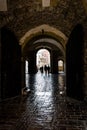 People walking along ancient pathway, silhouetted by external light