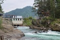 People walking along the bridge near old Chemal hydroelectric power station. Republic Altai, Russia, august 2017