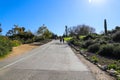 People walking along a long paved walking path in the garden with lush green trees and plants along the path