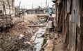 People walking along an open sewer in a slum in Africa Royalty Free Stock Photo