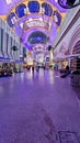 People walking along the street at the Fremont Street Experience with restaurants and retail stores and a video screen ceiling