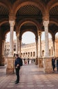 People walking amongst arches on Plaza de EspaÃÂ±a in Seville, Spain