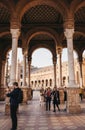 People walking amongst arches on Plaza de EspaÃÂ±a in Seville, Spain