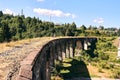 People walking on ancient bridge. Family of tourists on viaduct with old railway tracks near green hill of mountain forest. Locat Royalty Free Stock Photo