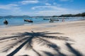 People walking on the beach, past boats with palm tree shadow, Bang Tao beach, Phuket, Thailand