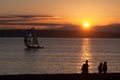 People walking on the beach with sailboat Royalty Free Stock Photo