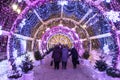 People walking through beautiful bright light tunnel in Moscow park during new year illumination