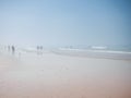 People walking on foggy beach with pink sand. Cadiz, Spain Royalty Free Stock Photo