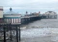 People walking on blackpool north pier on a stormy winter day at high tide