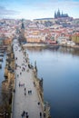 People are walking on Charles bridge, whose rooftops are covered by snow, Prague in the winter