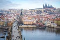 People are walking on Charles bridge, whose rooftops are covered by snow, Prague in the winter