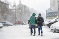 People walking through city street covered with snow during heavy snowfall. Blizzard in town at winter. Natural disasters, snow