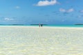 People walking through clear water over white sand South Pacific Island