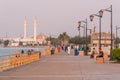 People walking down the Jeddah corniche in Saudi Arabia. Hassan Enany Mosque is seen on the background.