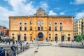 People walking down near Cinema Comunale Palazzo dell`Annunziata palace with clock on facade and fountain on Piazza Vittorio