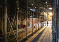 People walking down a sidewalk in New York City with the light of sunset shining through construction scaffolding