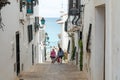 People walking down a steep path between two buildings with sea in the background in Altea, Spain.