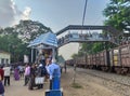 People walking through foot over bridge at Jhargram Railway station, West Bengal, India. Wide view of train