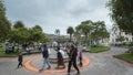 People walking in front of the fountain in the central park of Otavalo during a cloudy day