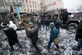 People walking inside the burned part of city with broked cars and buses in snow during winter anti-government protest Euromaidan