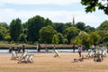 People walking and lounging in chairs in Hyde Park on a sunny day, London, UK