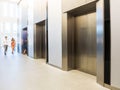 People are walking in office past elevators, Modern steel elevator cabins in a business lobby or