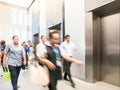 People are walking in office past elevators, Modern steel elevator cabins in a business lobby or