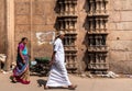People walking past ancient temple walls