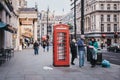 People walking past red phone booth in Haymarket, City of Westminster, London, UK